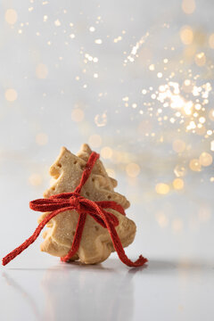 Christmas Tree  Shape Shortbread Cookies Stack With Red Ribbon On White Background With Gold Bokeh. Festive Treat