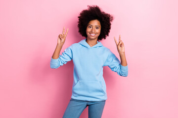 Photo of funny funky pretty girl wear trendy blue hoodie raise arm demonstrate v-sign greeting hi symbol isolated on pink color background