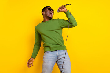 Portrait of handsome trendy cheerful guy singing single pop rock having fun isolated over bright yellow color background - obrazy, fototapety, plakaty