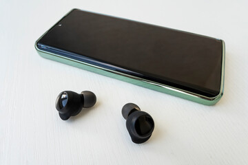 Smartphone and wireless headphones or earbudstop view. Music technology