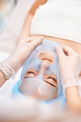 beautician removing mask from face of beautiful woman