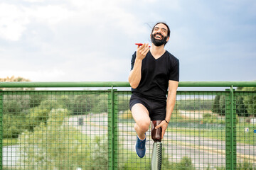 happy man laughing while using phone, young hispanic with an artificial leg relaxing at end...