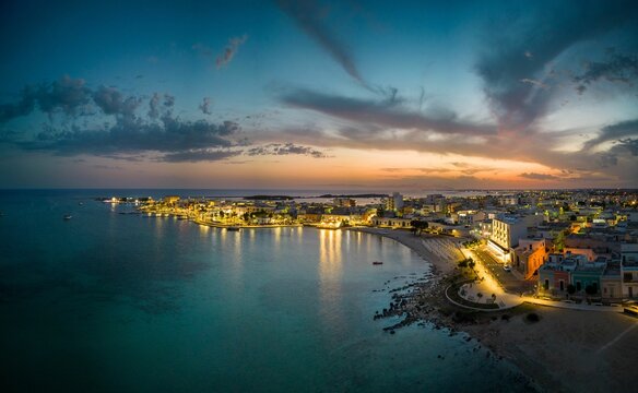 Fototapeta Aerial view of illuminated seaside cityscape of Porto Cesareo in Italy during sunset