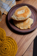 Clay plate of fried meat pies on wooden table.