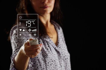 A woman in pajamas sets the temperature in the heating and air conditioning system of a bedroom, apartment or house. User interface on virtual screen.