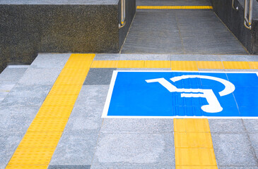 Disabled wheelchair sign with ramp and yellow tactile paving line on different level marble...