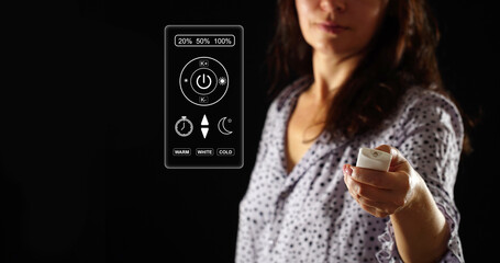 A woman in pajamas controls the lighting in the bedroom. User interface as virtual screen icon. Infrared light control panel.