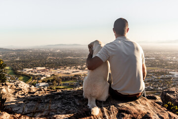 Man and dog on a hill overlooking a town - Powered by Adobe