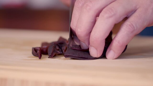 Chef slices wood ear mushrooms with sharp knife, close up low angle