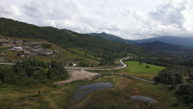 Drone moves horizontally captures the valley of Rauland, Telemark, Norway and a small settlement in the side