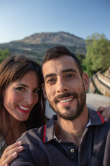 selfie of couple smiling, caucasian, dark-haired.  with nature background