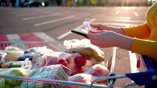 Woman checks paper check after shopping for groceries at mall by checking Dear Amount bill in a grocery cart. increase in food prices