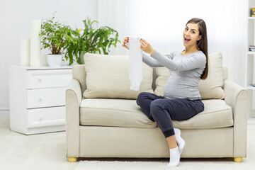 Obraz premium Photo of pregnant woman holding child small clothes.