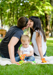 Happy family in the summer park. Mom, dad and baby son in the park