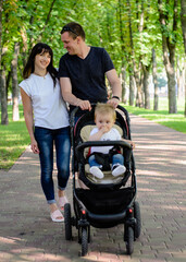 Happy family in the summer park. Mom, dad and baby son in the park