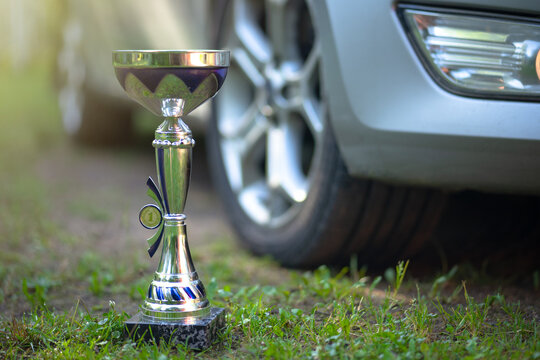 A cup for winning a car race. A big metal prize for the first place in a car race. Driving lessons at a driving school. Car driving skills.