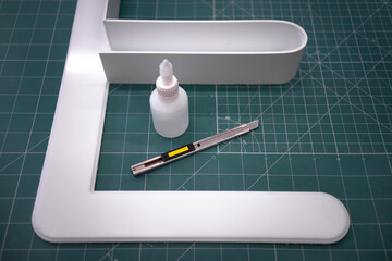Gluing a three-dimensional letter from white acrylic to make a logo. White polycarbonate on a green...