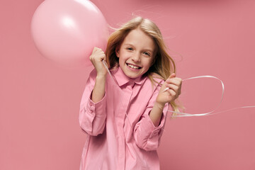 horizontal portrait of a cute beautiful, happy girl with a pink balloon in a pink dress on a pink background with an empty space for an advertising tex