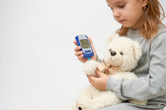 Little girl checking diabetes test to toy bear