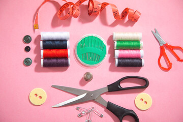 Sewing tools on the pink paper background.