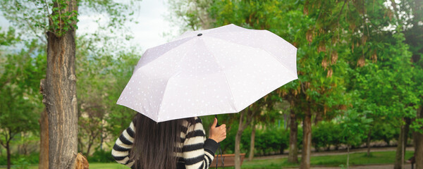 Caucasian woman holding umbrella in park.