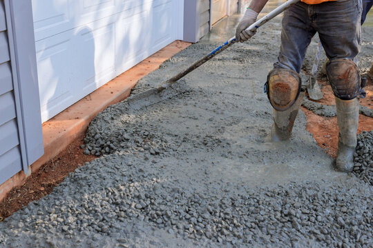 Construction contractors pouring wet concrete while paving driveway as they work on concrete construction project