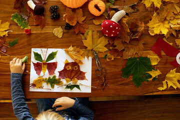 Child, applying leaves using glue, scissors, and paint, while doing arts and crafts at home