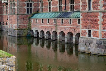 Historic beautiful Frederiksborg Castle arches over water in downtown Hilerod, Denmark