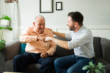 Very cheerful elderly father and son doing a fist bump and looking excited