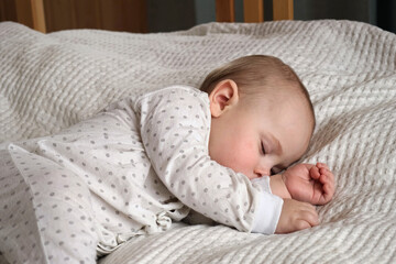 Peaceful adorable baby sleeping on his bed at home. Sleeping newborn baby concept. One year old baby girl sleeps peaceful at domestic room interior background. A serene dream. Face Close Up