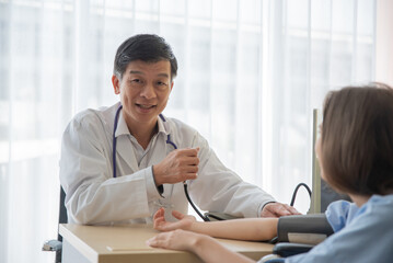 Obraz premium Doctor using sphygmomanometer checking blood pressure in hospital. Selective focus.