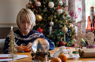 Kid peeling clementine against Christmas tree
