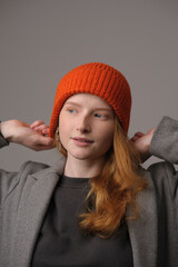 young girl model in orange cap and grey coat isolated on grey background. Product photo mockup for fashion brands and marketplaces.