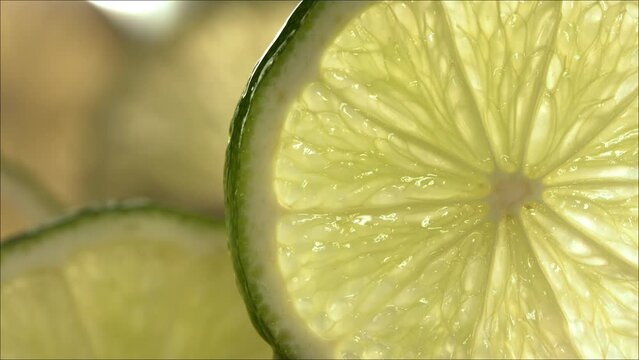 Drop of Lime Juice flow down the surface of a ripe juicy Lime slice. Slow Motion 4K