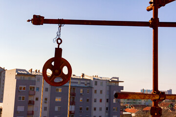 Round industrial pulley with rope for lifting load placed on the building site