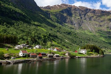 Bakka village with small houses in Norway next to a lake with trees and a river in the background