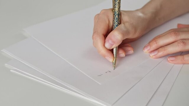 Hand with pen. A woman writes a numbered to-do variations list with a pen on a white blank sheet of paper. Day planning. Zoom in