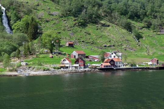 Bakka village with small houses in Norway next to a lake with trees and a river in the background