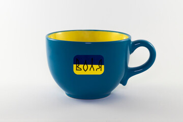 Empty decorative yellow and blue cup isolated on white background. State symbols of Ukraine are applied on the cup. Close-up. State flag of Ukraine. Stand with Ukraine