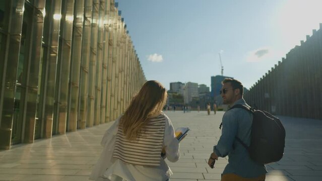 Two Young Adult Students Meet Up and Walk Together After Lectures in University Area at Sunset - slow motion tracking shot
