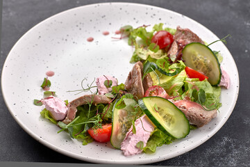Salad with veal and cream cheese, on a white plate and a dark background