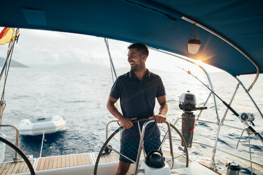 Smiling skipper sailing on yacht, copy space