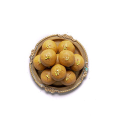 Besan ladoo or laddu in a gold plate are delicious sweet balls made with gram flour, sugar, ghee cardamoms, indian mithai made on diwali festival