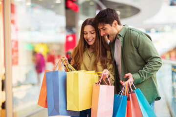 Excited Buyers Couple Looking Inside Shopping Bags In Modern Hypermarket