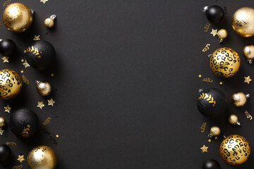 Luxury Christmas background with gold and black baubles and confetti on dark table. Elegant Merry...