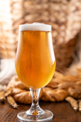 . Glass of light craft beer on a wooden table. Beer is poured into a glass with foam and bubbles. Vertical. for social media or advertising. beer texture. 