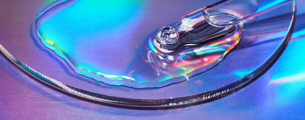 Pipette with cosmetic product on holographic banner, iridescent highlights, selective focus