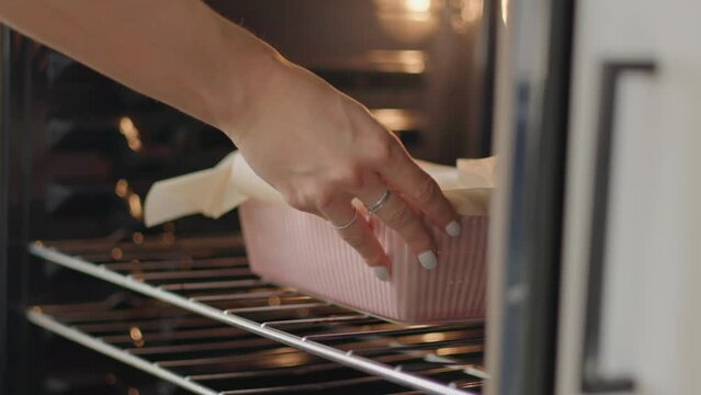 Close up, girl placing fall baking recipe in oven