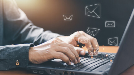 Businessman hands using Laptop typing on keyboard and surfing the internet on office table with email icon, email marketing concept, send e-mail or newsletter, online working internet network.