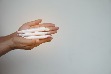 Closeup hands hold  sanitary pads for menstruation. Concept: female's hygienic product for period's day. Woman healthcare. Monthly intimate hygiene.  - obrazy, fototapety, plakaty
